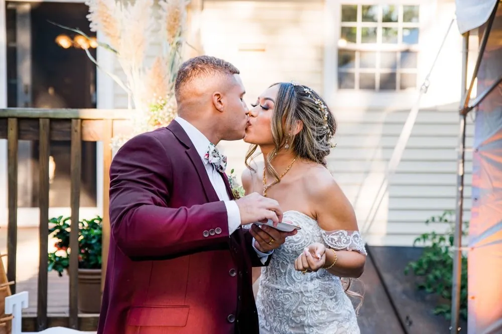 Tatiana and Tyler share a kiss beside the dessert table next to the house