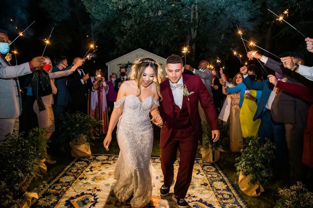 Tatiana and Tyler walk the rug aisle through a tunnel of sparklers at night