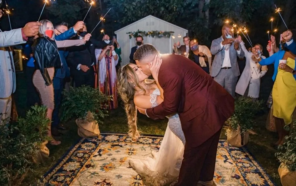 Tyler dips Tatiana for a kiss on the Persian rug as guests hold sparklers overhead