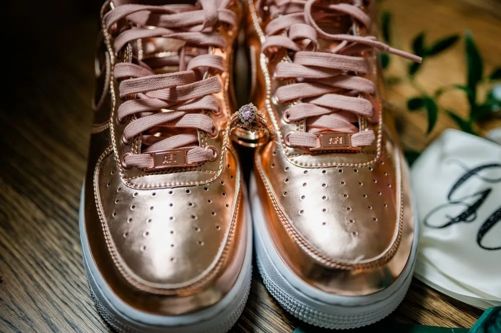 Rose gold high-top sneakers on a wood floor next to the rings