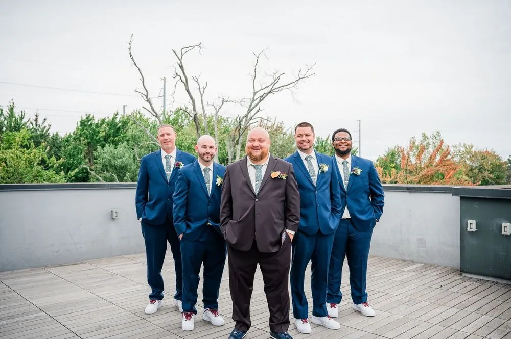 The groom with groomsmen in blue suits on the brewery's upstairs deck