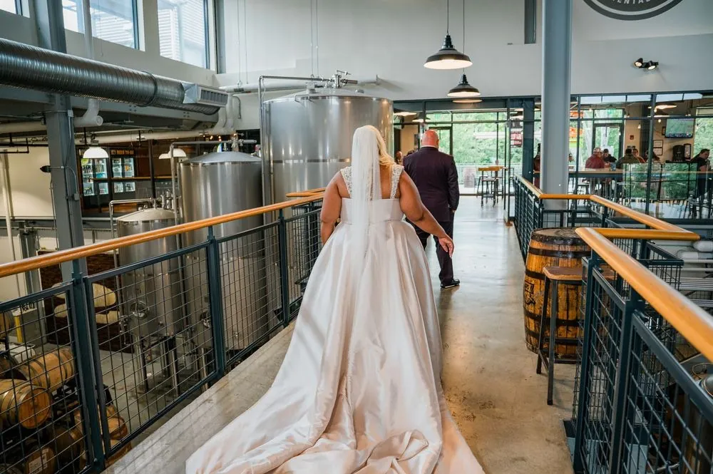 The bride walks along the catwalk above the brewery's steel tanks