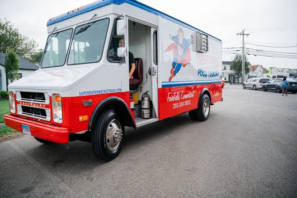 A red and white food truck parked in the brewery lot for dinner