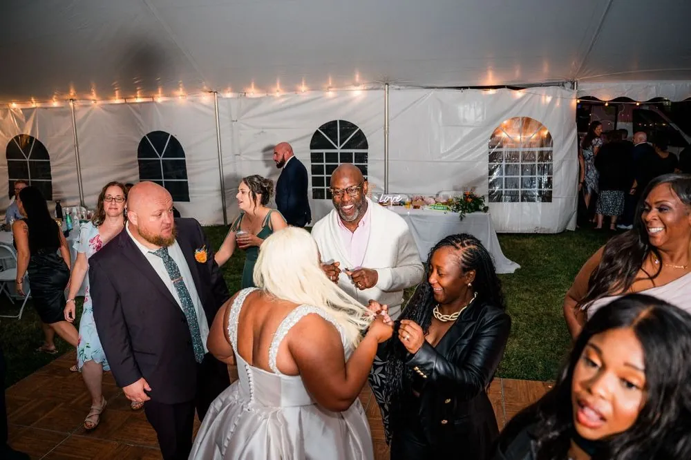 Guests dance under the white tent strung with bulb lights