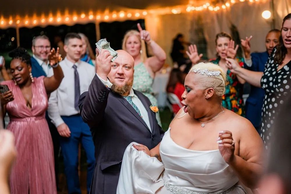 The couple dances in the middle of a cheering crowd under the tent