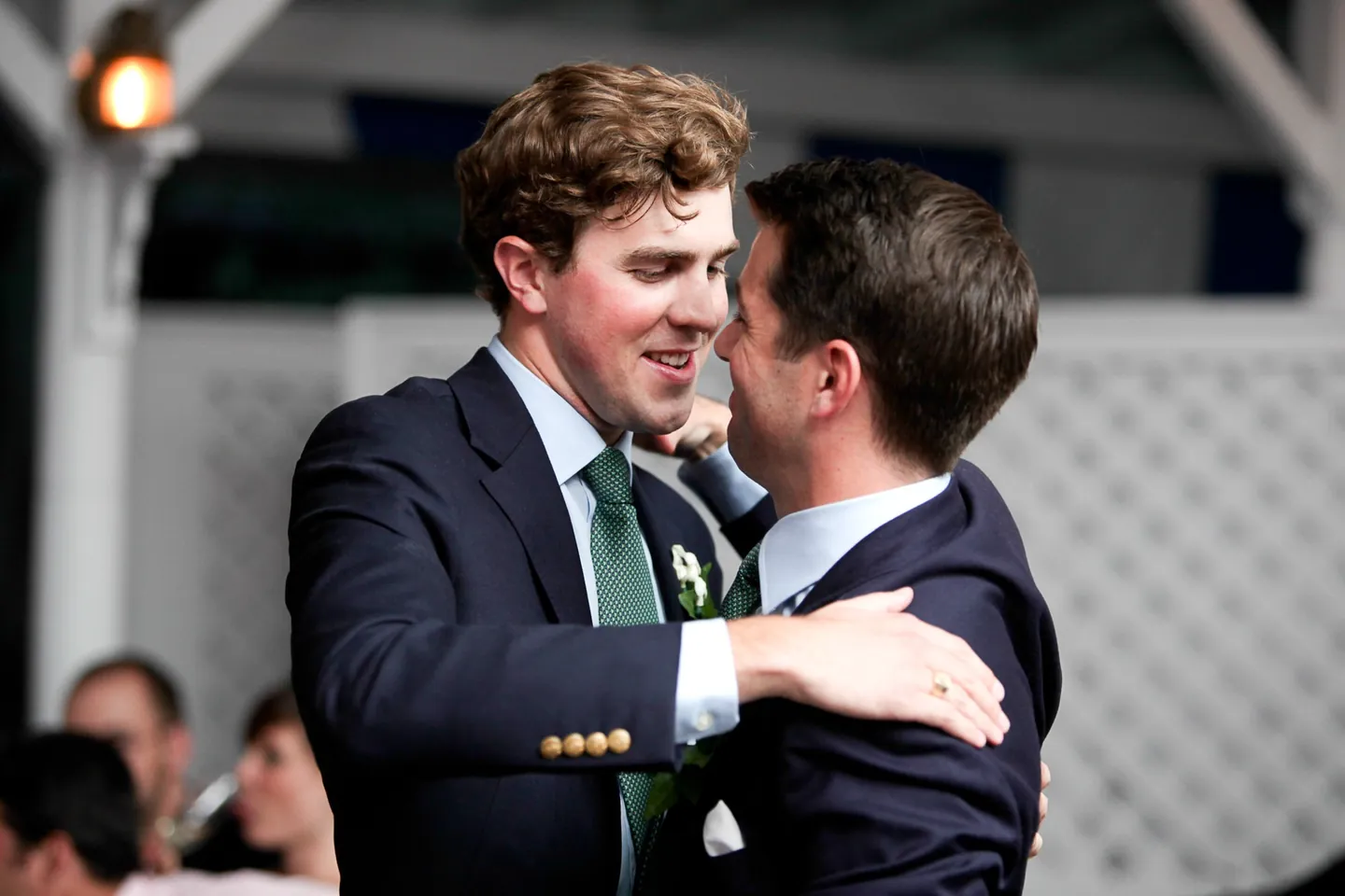 The groom pulls a friend into a big hug on the edge of the dance floor