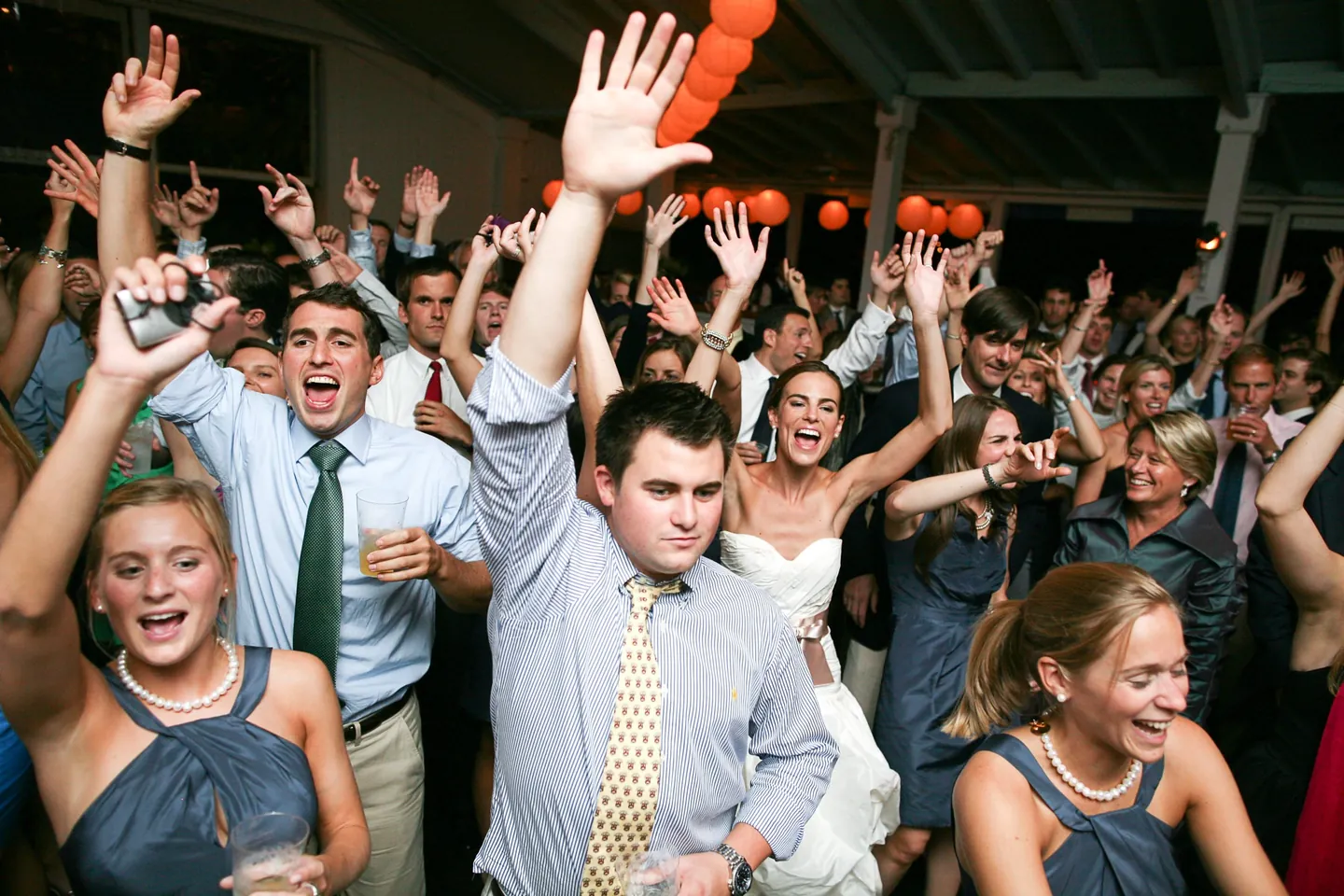 A packed dance floor of guests throwing their hands up and shouting along