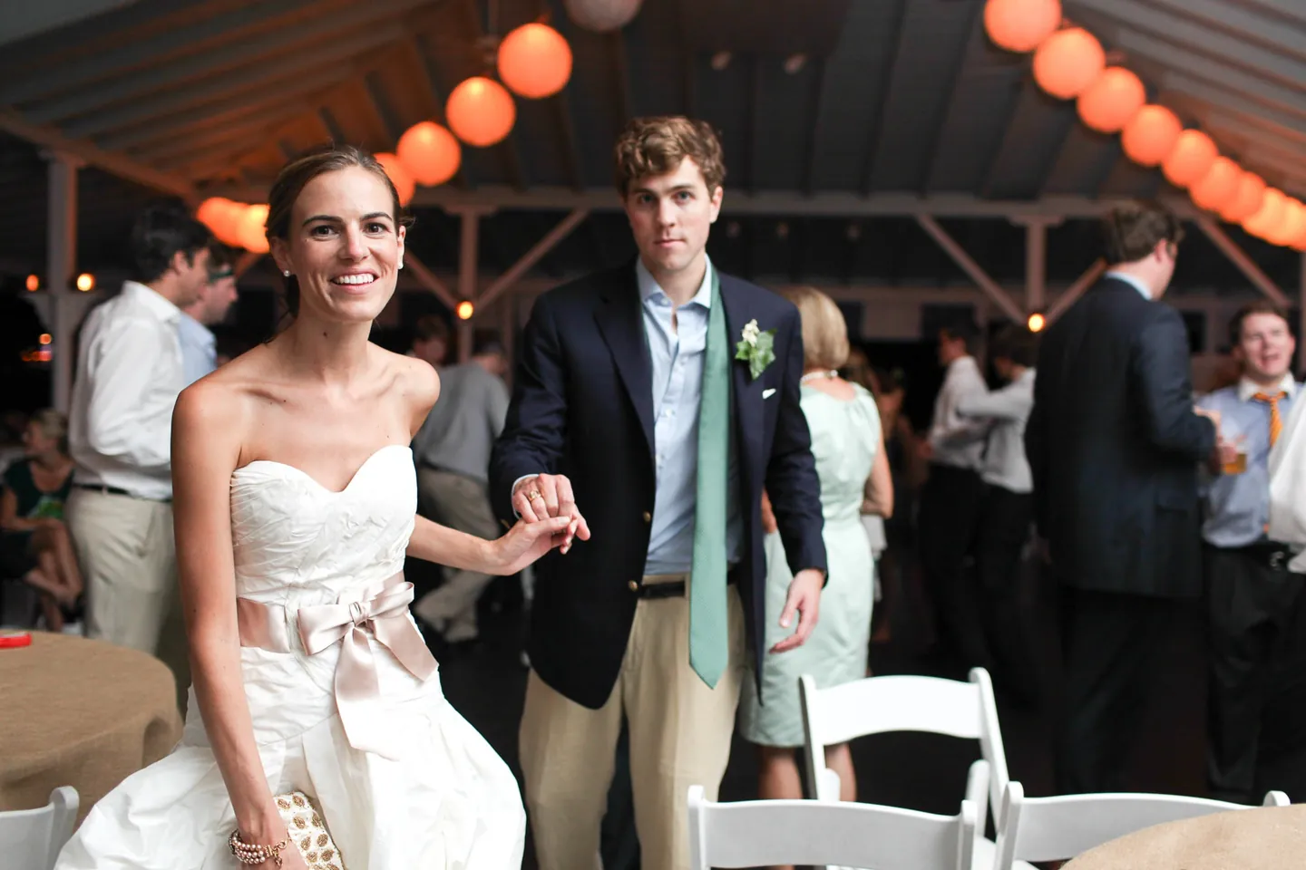 Trevor and Christina laugh walking hand in hand through the crowd