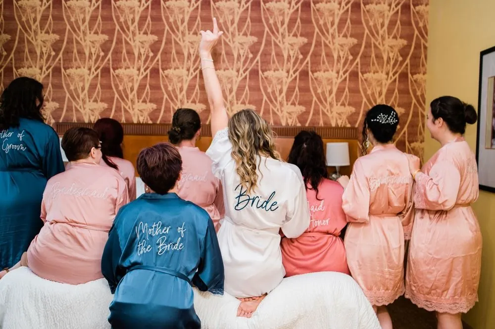 The bride and bridesmaids in robes cheer with their backs to the camera
