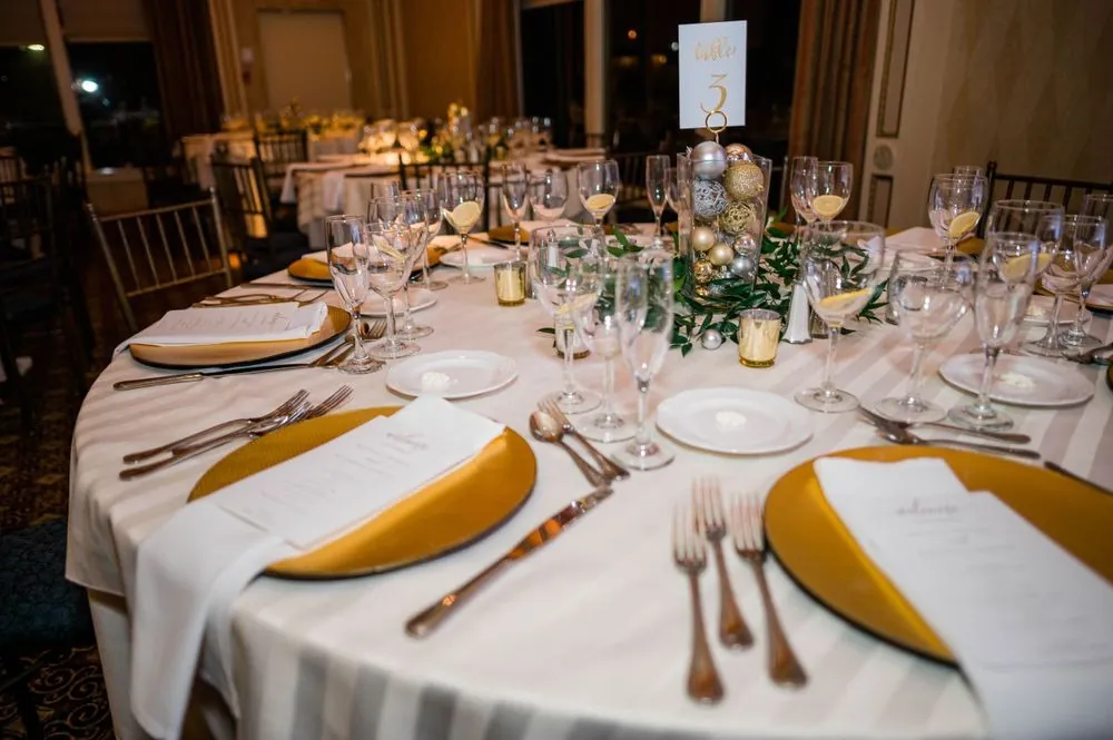 Reception table set with gold chargers, gold napkins, and crystal glassware