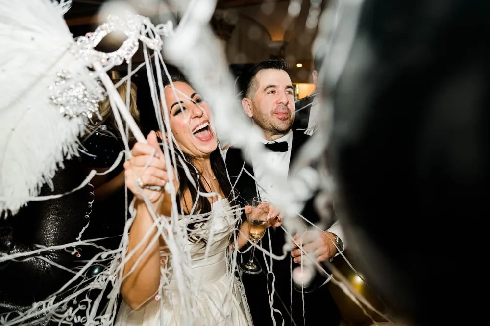 Michele and Nicholas celebrate tangled in white streamers after the balloon drop