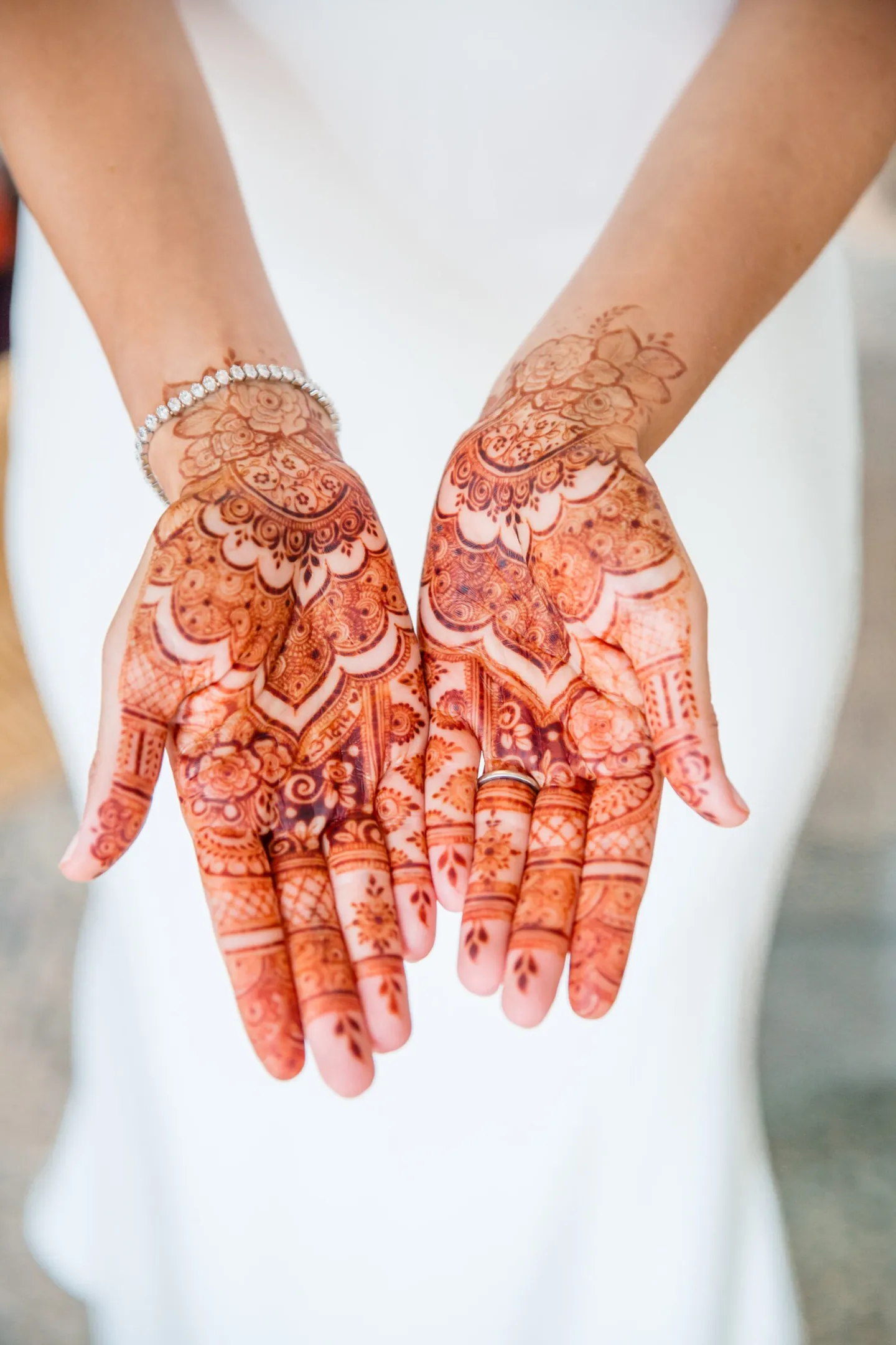 The bride holds her henna-painted palms open in front of white fabric