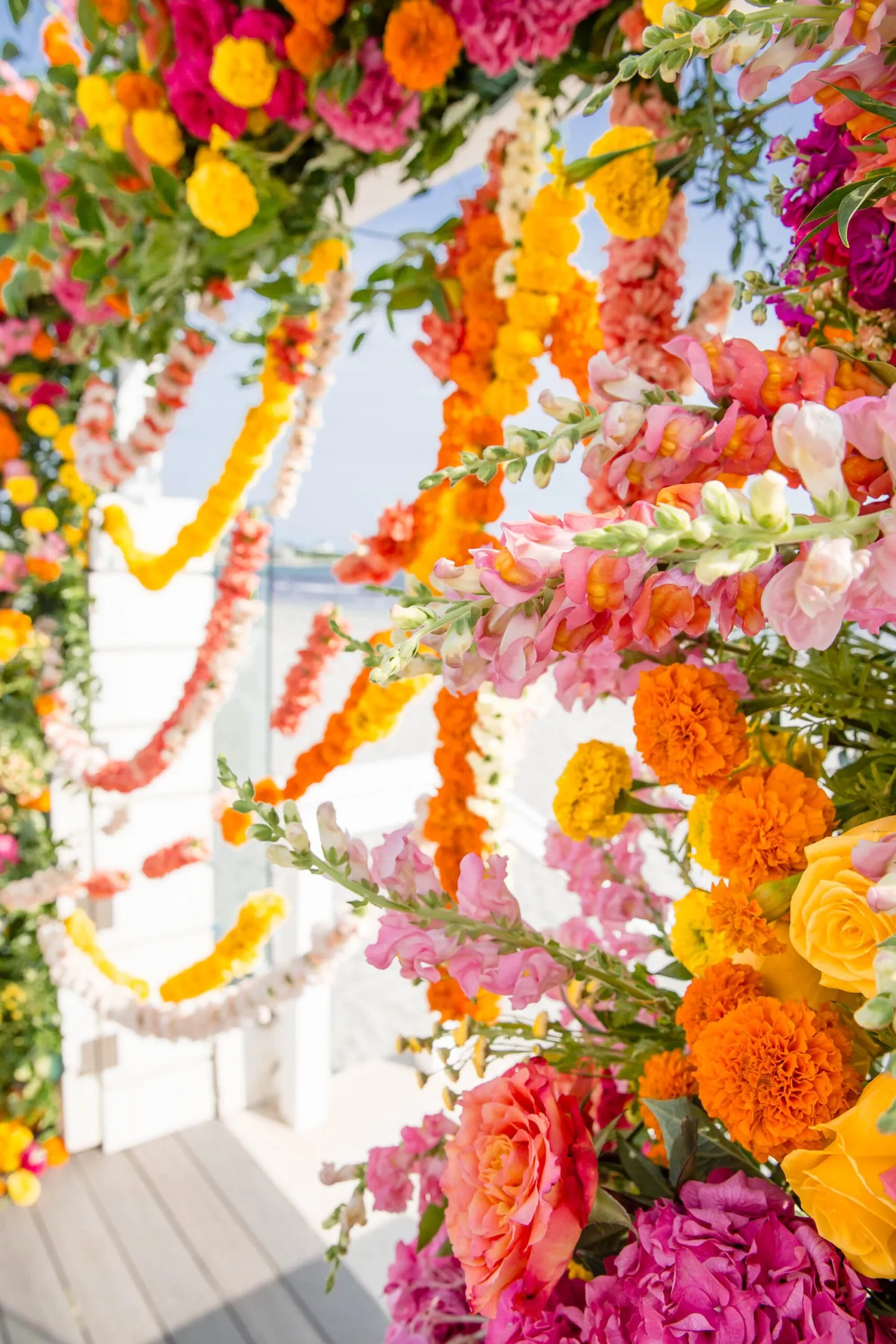 Close view of the arch corner, marigold strands hanging among pink roses and orange blooms