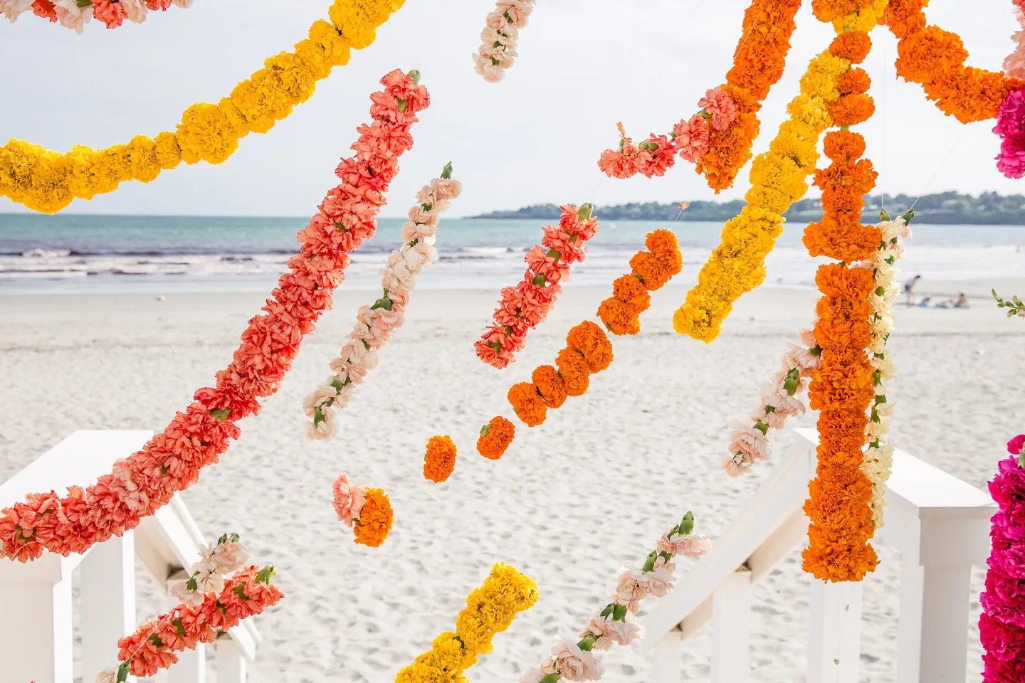 Orange and yellow marigold garlands sway in the foreground above the beach