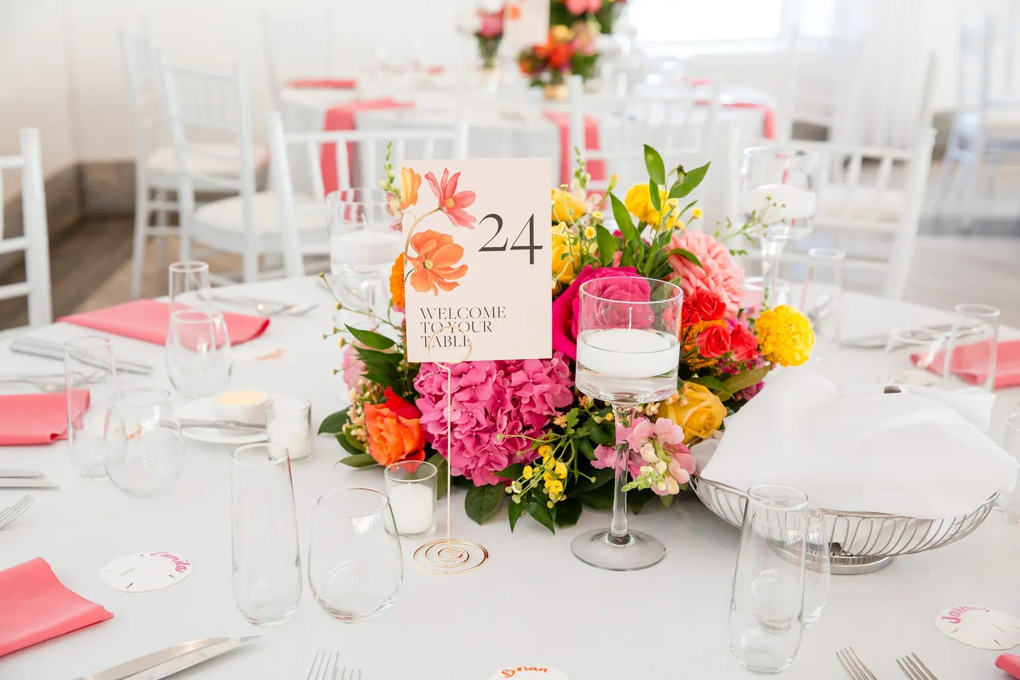 Table 24 card set in a low arrangement of coral roses and orange blooms